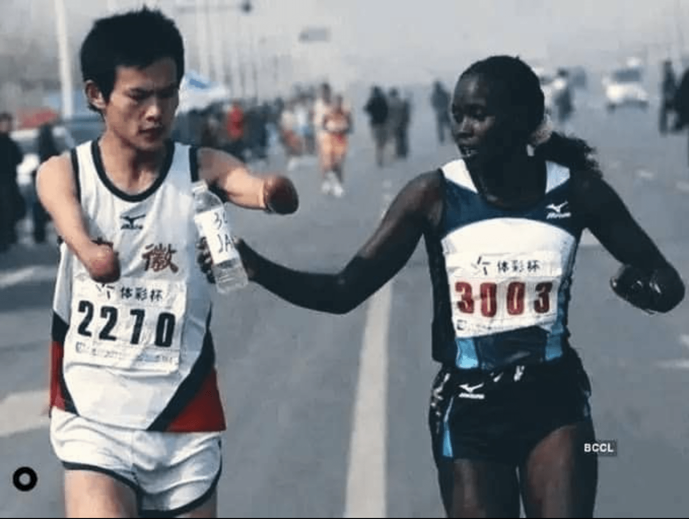 Elite runner Jaqueline Kiplimo helps a disabled Chinese athlete drink during the 2010 Zheng-Kai marathon.